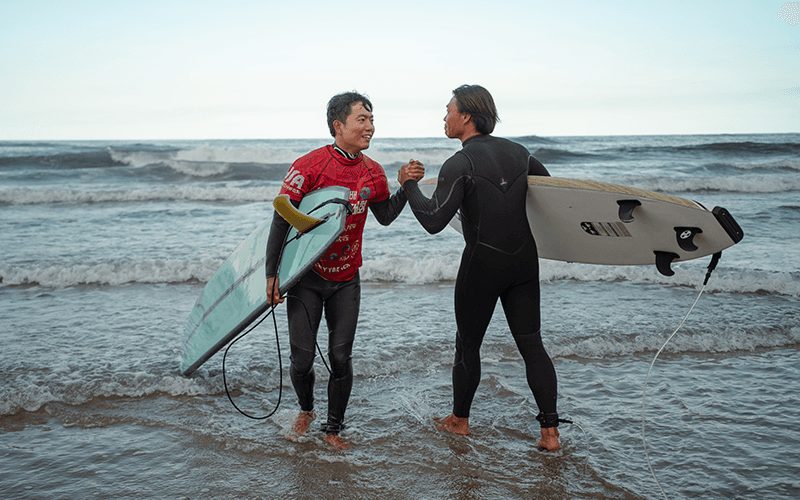 서퍼들이 해변에서 하이파이브하는 모습